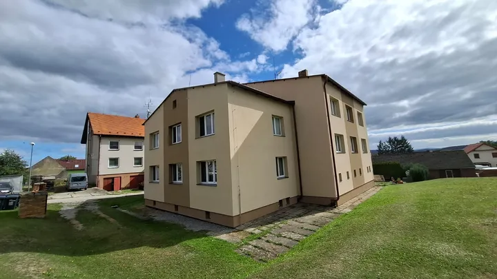 Bytový dům v Ločenicích po rekonstrukci, zadní roh s novou fasádou a hnědým soklem