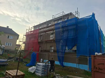 Bytový dům v Ločenicích během prací na fasádě, lešení se sítěmi a materiál na stavbě