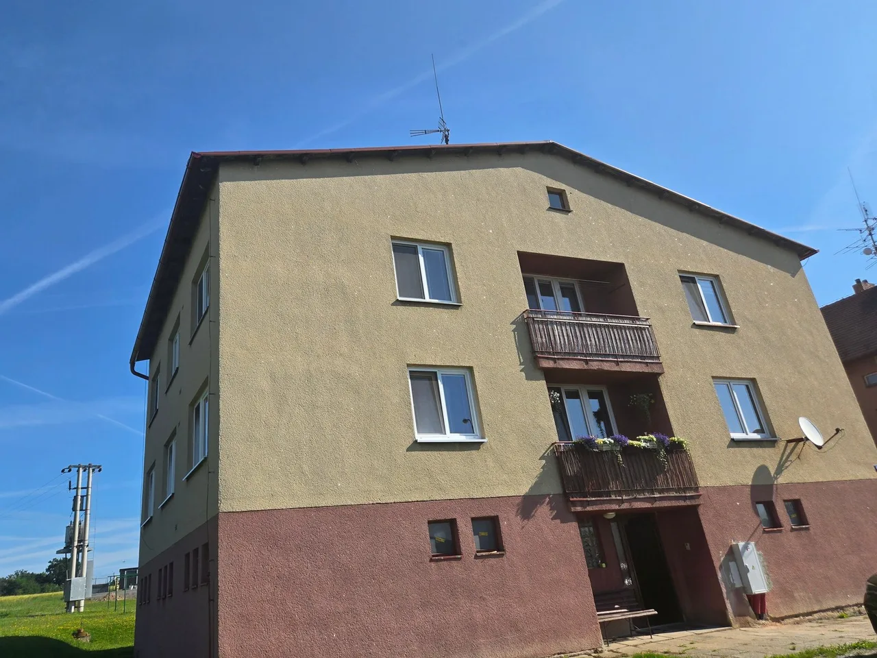Bytový dům v Ločenicích před rekonstrukcí, zašlá fasáda a dřevěná zábradlí balkonů