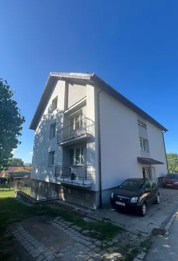 Bytový dům v Otěvěku po rekonstrukci, roh s balkony, nová světlá fasáda a nová střecha