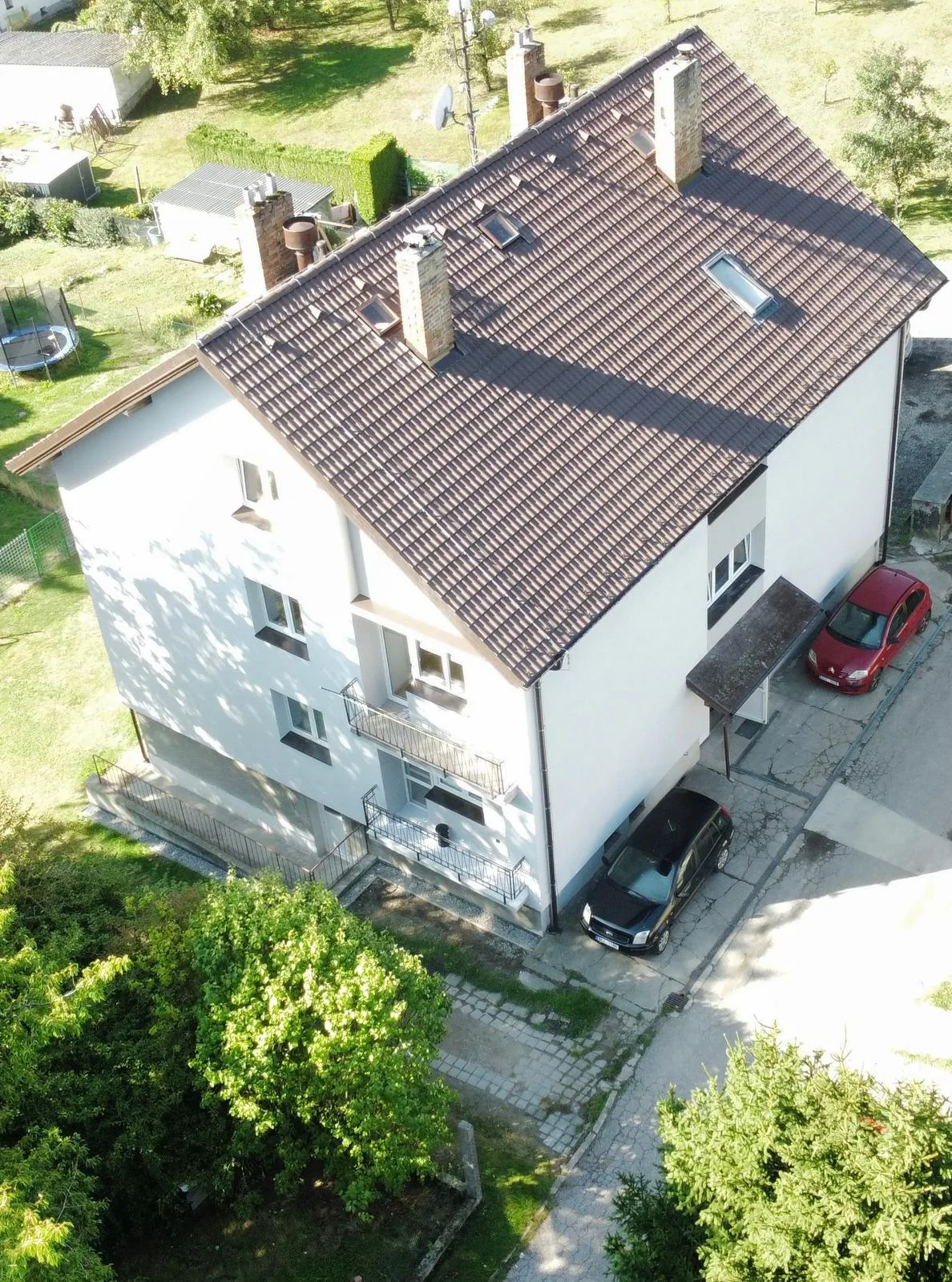 Nová střecha z betonových tašek a fasáda bytového domu v Otěvěku, šikmý pohled dronem