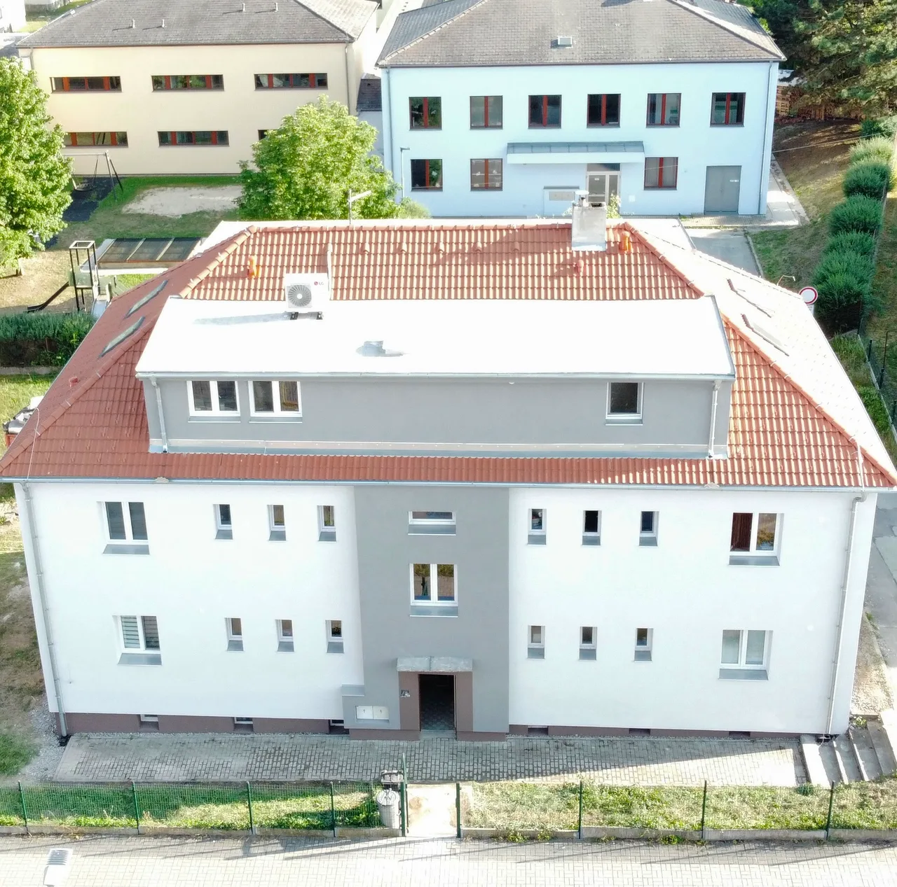 Bytový dům ve Zlivi po rekonstrukci, pohled z výšky na novou fasádu a střechu