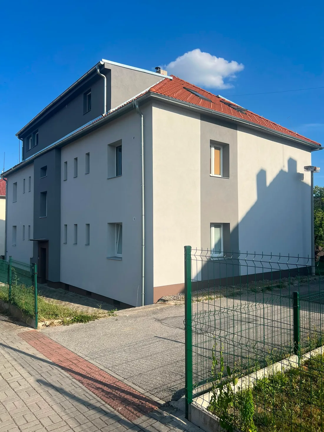 Stejný roh bytového domu ve Zlivi s novou fasádou a soklem