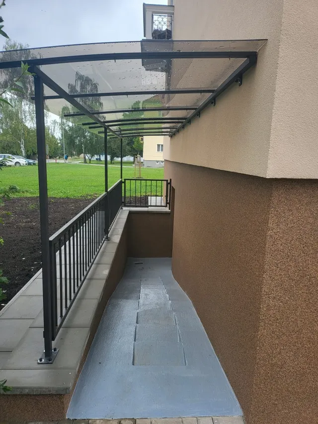 Boční vstup bytového domu na Libuši v Bechyni po rekonstrukci, nová fasáda s hnědým soklem