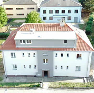 Bytový dům ve Zlivi po rekonstrukci, pohled z výšky na novou fasádu a střechu