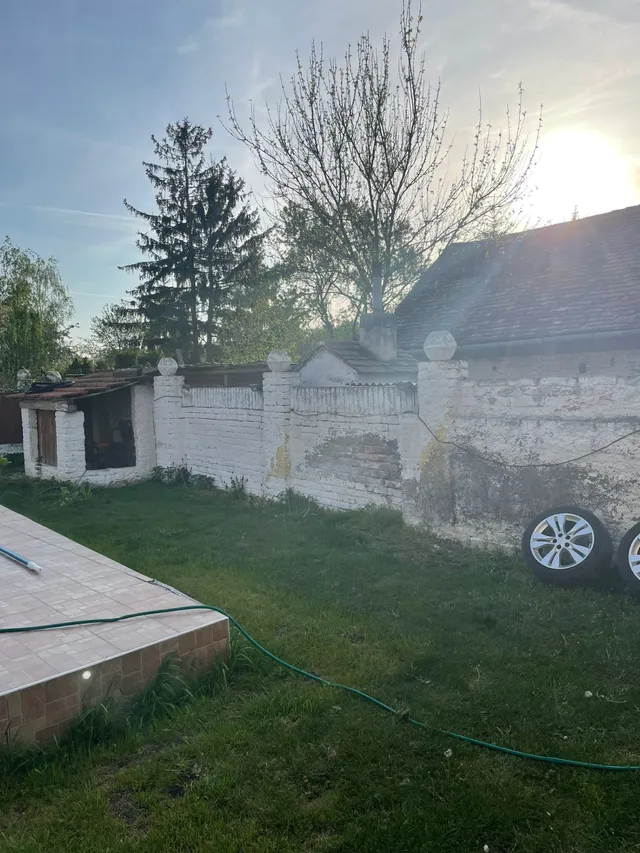 Dvůr usedlosti před rekonstrukcí, oprýskaná zeď a stará kůlna